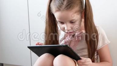 情绪化的女孩正在用平板电脑玩电子游戏。 儿童电子小玩意画像